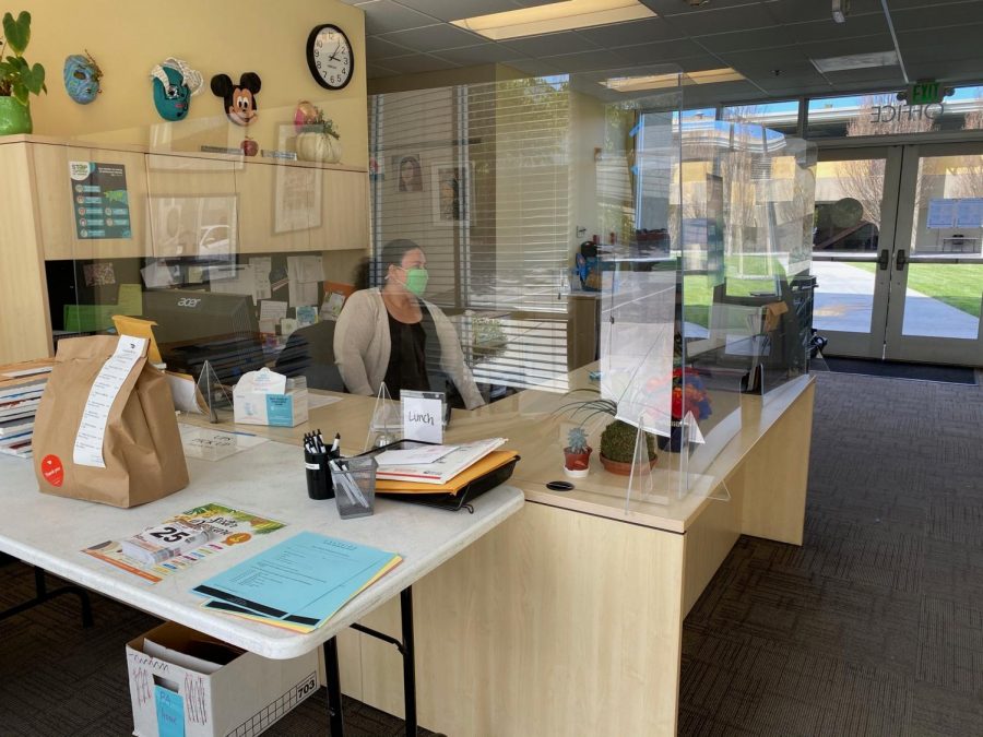 Office Manager Janelle Fine working behind a protective shield in the front office. 