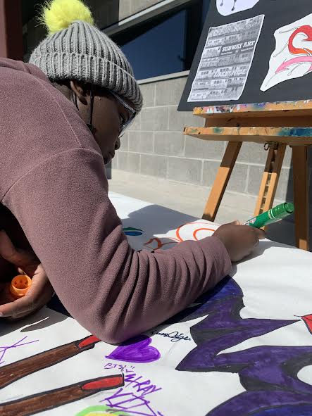 Freshman Emma Adjei illustrating her name on graffiti poster during the First Friday on Oct. 7.